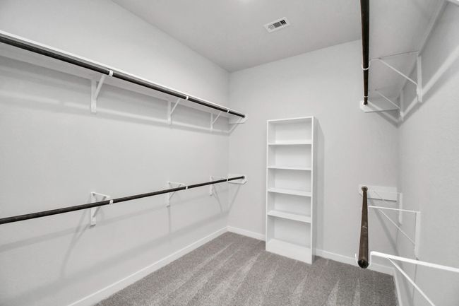 Walk-in closet that epitomizes luxury and practicality. This generously sized space features built-in shelving, offering abundant room for impeccable organization. High ceilings and recessed lighting create a bright and welcoming ambiance. | Image 29