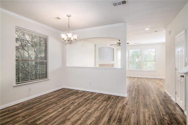 Unfurnished room with wood finished floors, a chandelier, ceiling fan, ornamental molding, and arched walkways | Image 7
