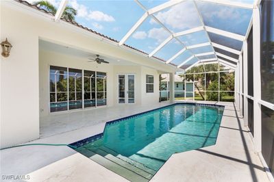 View of swimming pool featuring glass enclosure, ceiling fan, and a patio area | Image 2