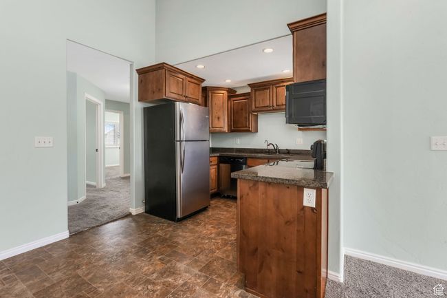 Kitchen featuring dark colored carpet, stainless steel appliances, baseboards, dark countertops, and recessed lighting | Image 7