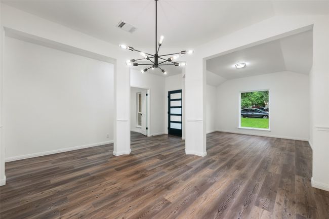 Unfurnished living room with a chandelier, dark wood-style flooring, and vaulted ceiling | Image 10