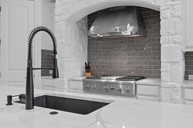 Kitchen featuring wall chimney exhaust hood, range, and white cabinets | Image 4