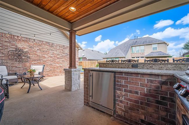 An alternate view of the covered patio highlights the rich tongue-and-groove stained wood ceiling and a striking stone-wrapped pillar—adding warmth and architectural charm to the space. | Image 40