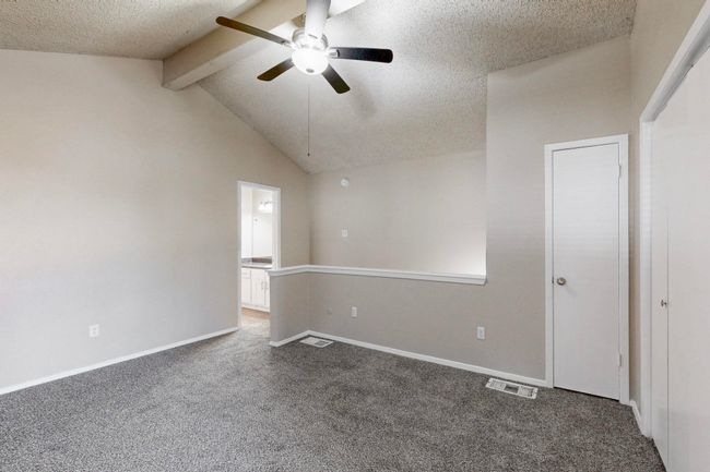 Empty room featuring visible vents, a textured ceiling, carpet flooring, ceiling fan, and vaulted ceiling with beams | Image 31