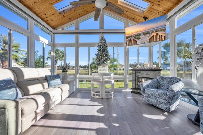 Sunroom / solarium with a skylight, wood finished floors, wood ceiling, and high vaulted ceiling | Image 25