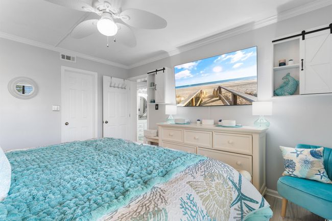 Bedroom featuring a barn door, wood finished floors, ornamental molding, baseboards, and a ceiling fan | Image 15