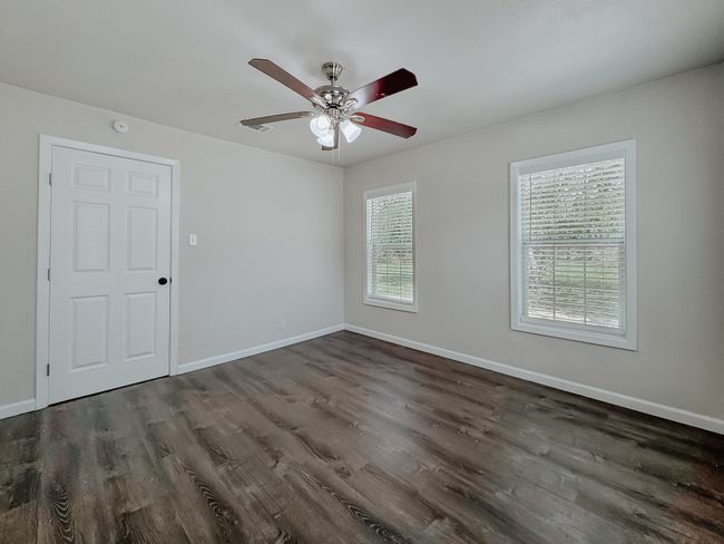 Empty room with dark wood-style flooring, a ceiling fan, and a smoke detector | Image 18