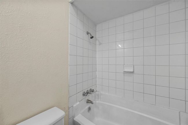 Bathroom featuring shower / bathtub combination and a textured wall | Image 13