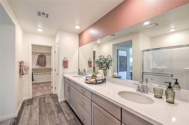 Bathroom with wood finished floors, a spacious closet, double vanity, a shower with door, and recessed lighting. Photo is representational only; actual home finishes may vary. | Image 25