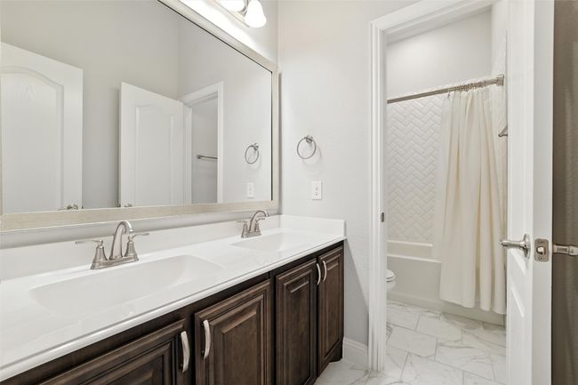 Bathroom featuring marble finish floors, double vanity, and shower / tub combo with curtain | Image 29