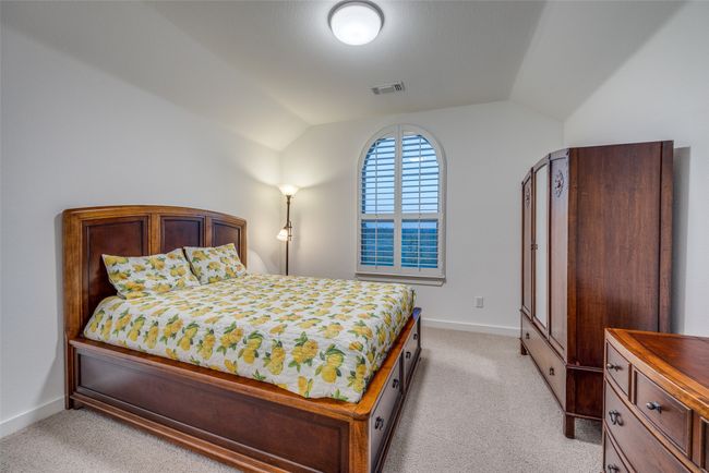 Bedroom with visible vents, baseboards, light colored carpet, and lofted ceiling | Image 30