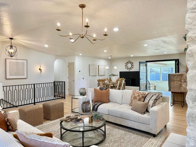 Living room featuring arched walkways, a chandelier, a textured ceiling, light wood-type flooring, and recessed lighting | Image 8