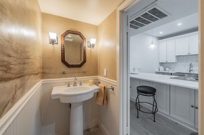 Bathroom featuring a wainscoted wall, visible vents, a sink, and backsplash | Image 5