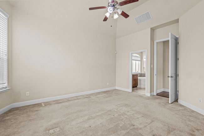 Unfurnished bedroom featuring light carpet, baseboards, ensuite bathroom, and a ceiling fan | Image 17