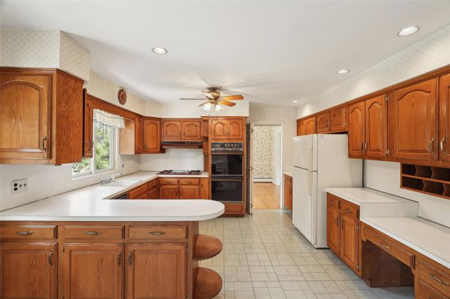 Kitchen featuring wallpapered walls, light countertops, a ceiling fan, freestanding refrigerator, and dobule oven black | Image 10