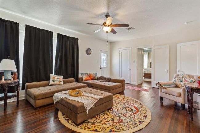 Living room featuring dark wood-style flooring, visible vents, and a ceiling fan | Image 20