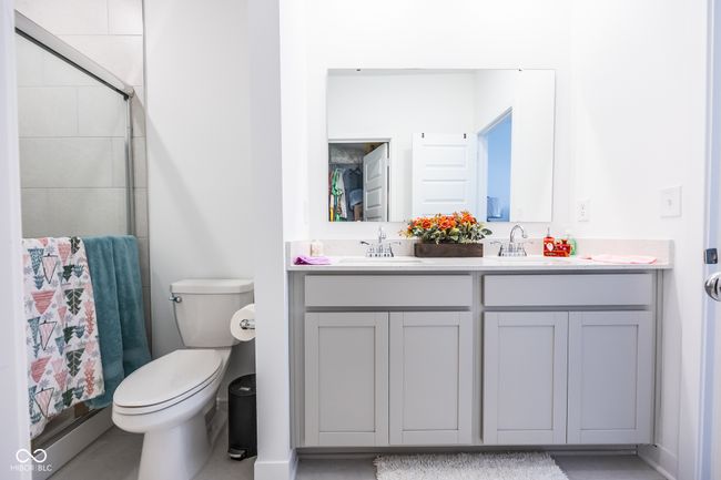 full bath with double vanity, a tile shower, and toilet | Image 14