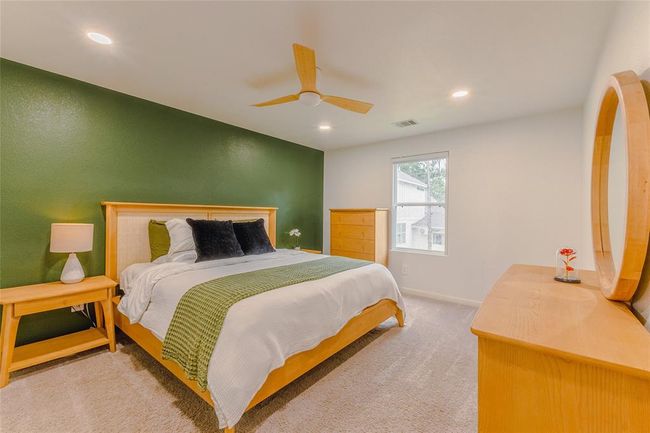 The primary bedroom is located on the second floor and has room for an additional seating area or maybe a crib for a baby. The primary has smart blackout blinds! This room has recessed lighting and a sleek ceiling fan ready to cool the air. | Image 15