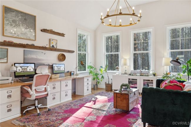 Office area featuring vaulted ceiling, a notable chandelier, light wood-style floors, and built in desk | Image 17