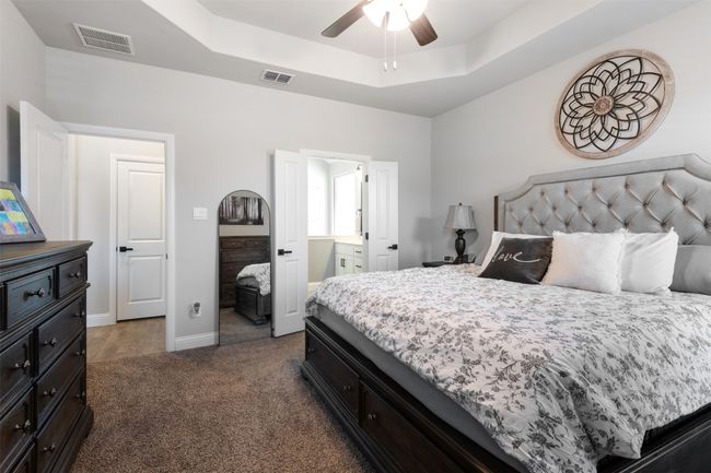 Bedroom featuring carpet, a raised ceiling, and visible vents | Image 23