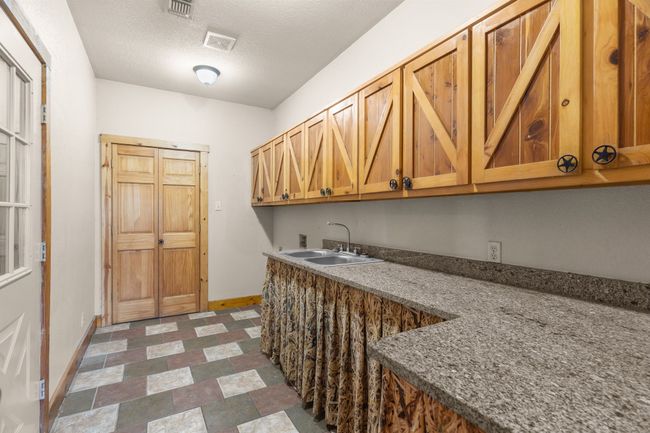Laundry area with hookup for a washing machine, a textured ceiling, a sink, baseboards, and cabinet space | Image 31