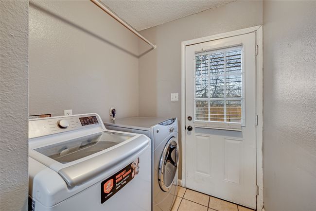 Unit B featuring washer and dryer, a textured ceiling, and light tile patterned flooring | Image 22