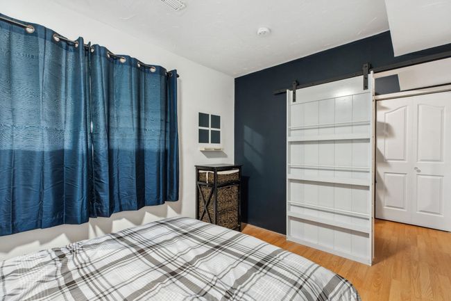 Bedroom with a barn door and wood finished floors | Image 25