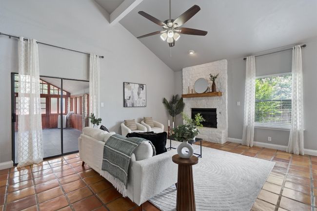 Living room with a ceiling fan, a fireplace, beam ceiling, tile patterned floors, and high vaulted ceiling | Image 7