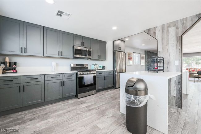 Kitchen with stainless steel appliances, light countertops, light wood-style flooring, gray cabinets, and recessed lighting | Image 23
