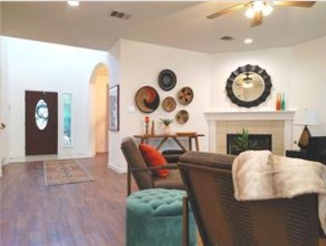 Living area with arched walkways, wood finished floors, ceiling fan, a fireplace, and baseboards | Image 21