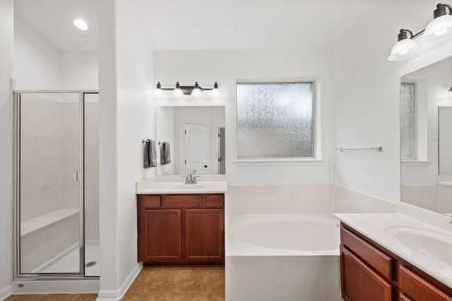 Bathroom with a stall shower, a bath, two vanities, and tile patterned floors | Image 27