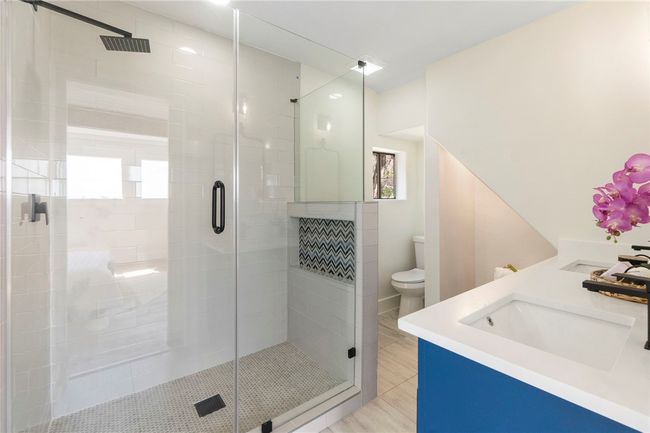 The guest bathroom is equipped with a quartz-topped dual vanity and a frameless walk-in shower. | Image 23