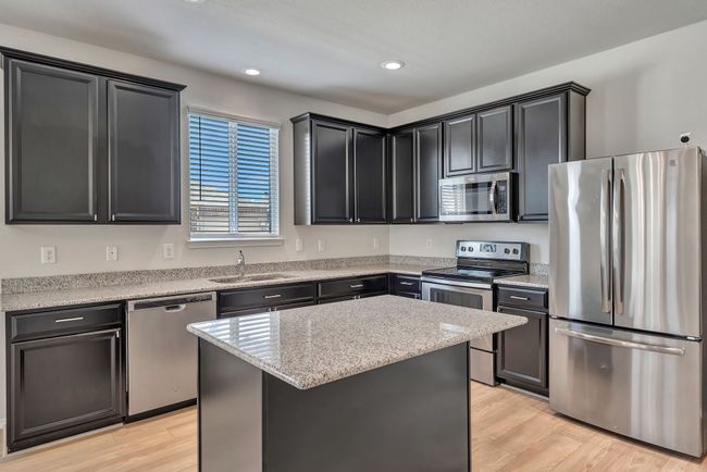 Kitchen featuring stainless steel appliances, light wood-style floors, a kitchen island, recessed lighting, and dark cabinets | Image 8