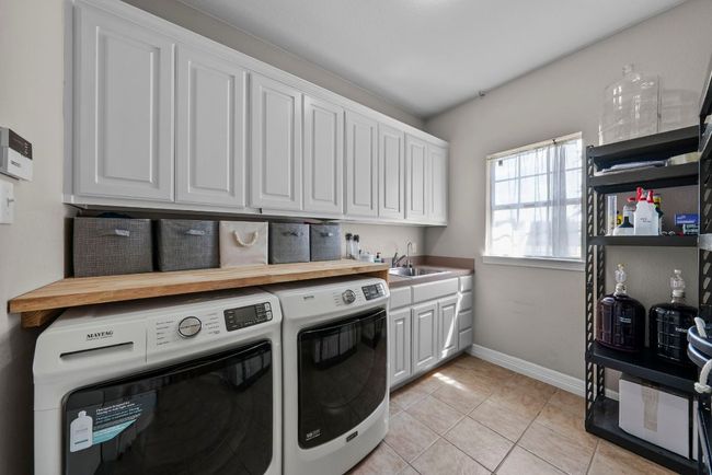 the oversized utility room includes a convenient sink & loads of extra cabinets for storage | Image 23
