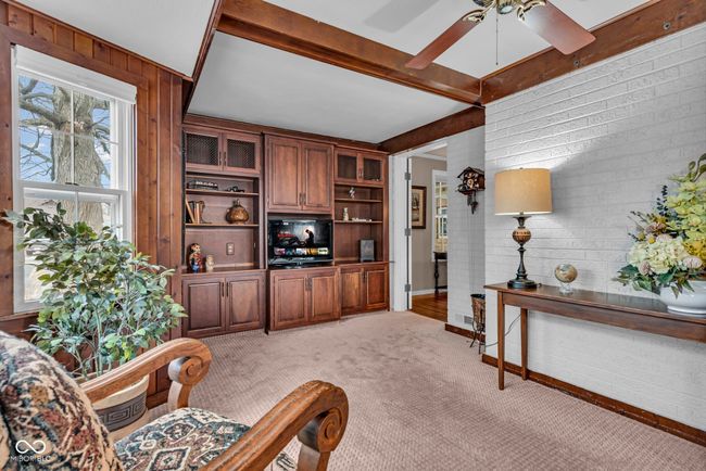 living area featuring wooden walls, light carpet, a ceiling fan, and beam ceiling | Image 5