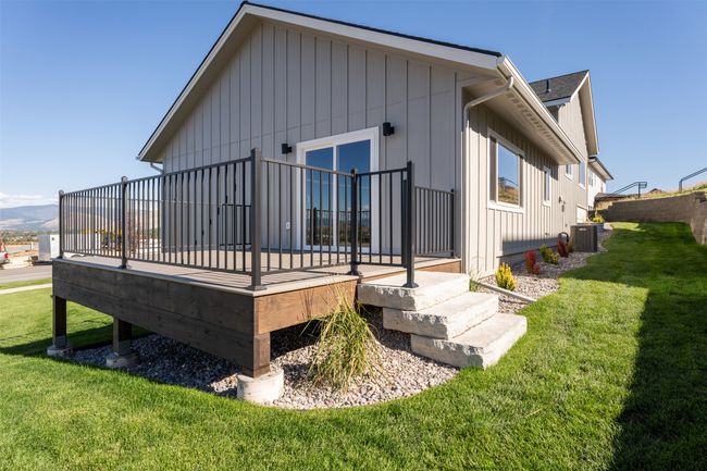 Rear view of house featuring a deck, a lawn, central AC, and board and batten siding | Image 7