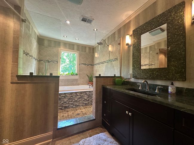 full bath featuring crown molding, a textured ceiling, a bath, vanity, and tiled shower | Image 31