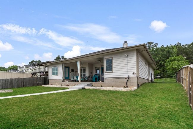 This photo shows a charming single-story home with a covered patio, ample backyard space, and a fenced perimeter, ideal for outdoor activities and relaxation. | Image 28