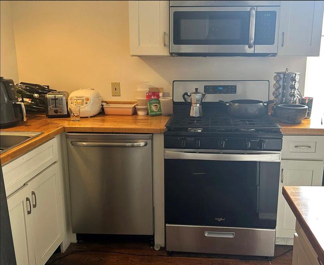 Kitchen with appliances with stainless steel finishes, wooden counters, and white cabinets | Image 4
