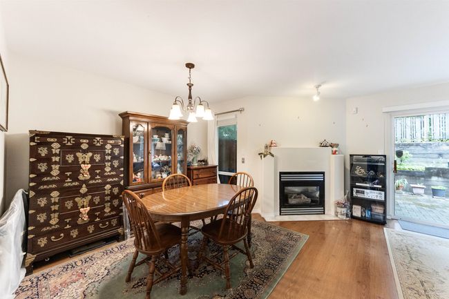 Dining space featuring wood finished floors, a chandelier, and a fireplace with flush hearth | Image 8