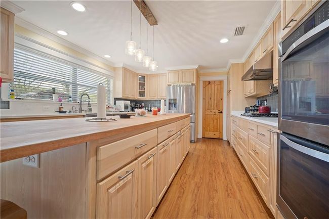 Kitchen with butcher block countertops, stainless steel appliances, under cabinet range hood, and visible vents | Image 12