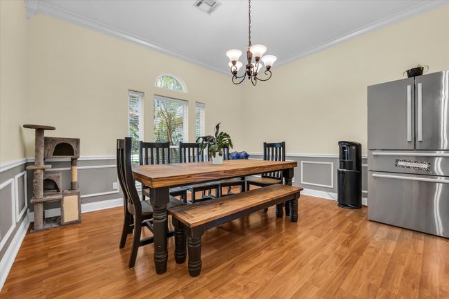Dining area with ornamental molding, a chandelier, light wood-type flooring, a decorative wall, and a wainscoted wall | Image 6