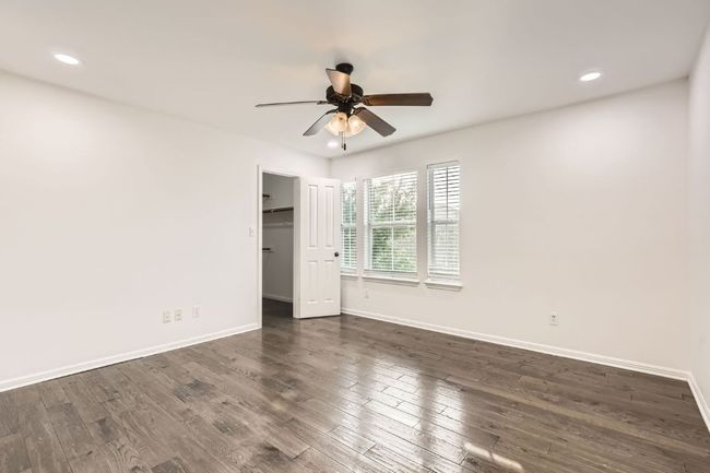 Unfurnished bedroom featuring baseboards, dark wood-type flooring, recessed lighting, a walk in closet, and ceiling fan | Image 19