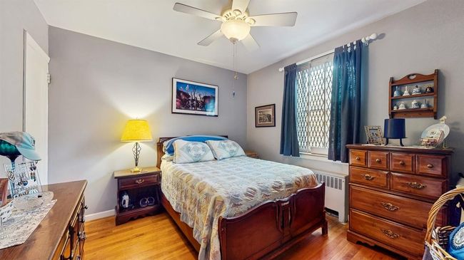 Bedroom with light wood-style flooring, radiator, and ceiling fan | Image 16