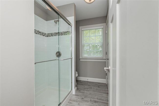 Full Bathroom with toilet, wood finished floors, a shower stall, and baseboards | Image 37
