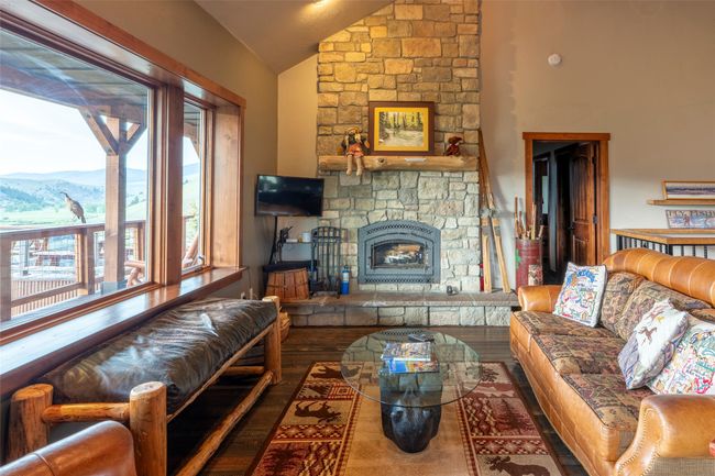 Living room with lofted ceiling, a mountain view, a stone fireplace, and wood finished floors | Image 11
