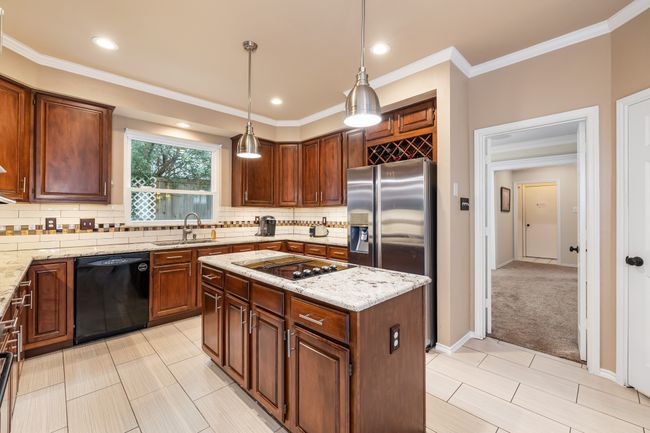 Kitchen featuring black appliances, a kitchen island, crown molding, tasteful backsplash, and pendant lighting | Image 19