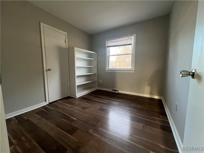 Unfurnished bedroom featuring dark wood-style floors, visible vents, and baseboards | Image 9