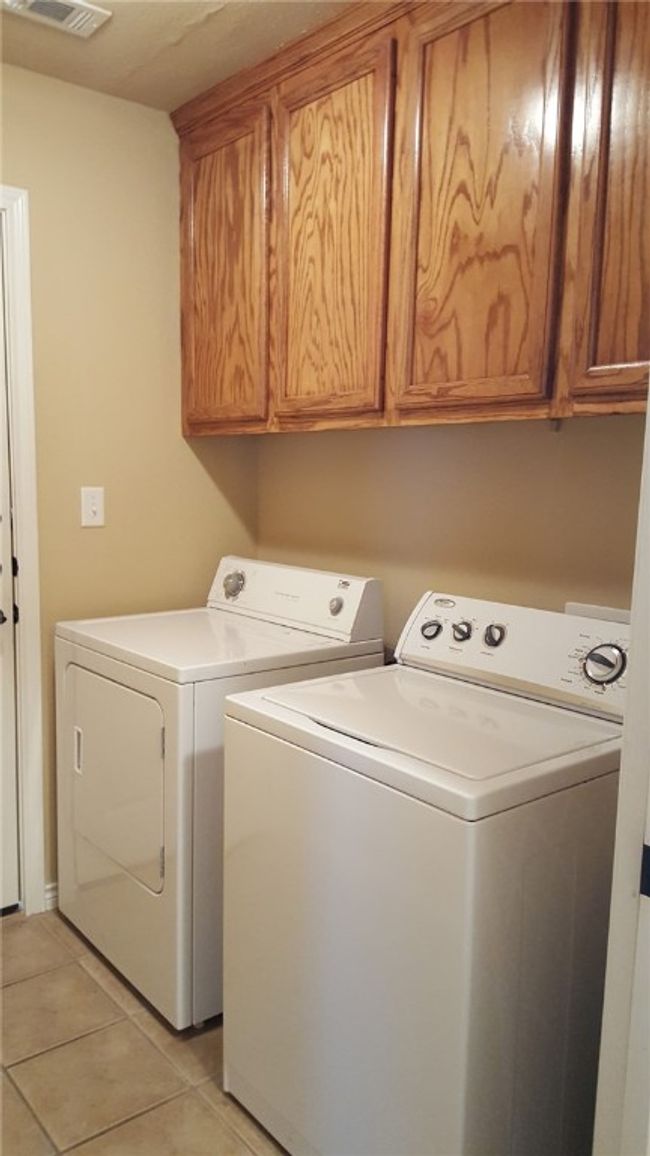 Laundry room featuring washer and dryer, cabinet space, and light tile patterned flooring | Image 12