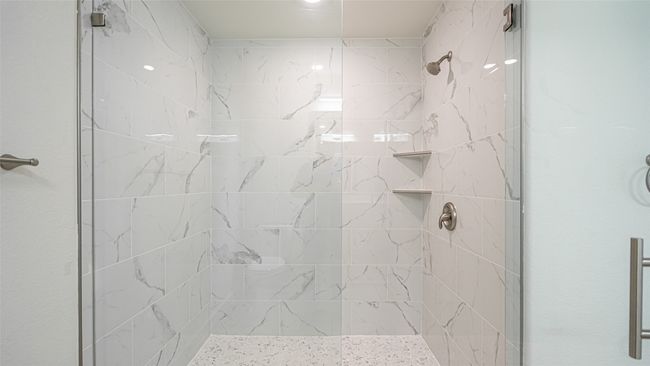 Huge primary shower with plate glass doors, marble walls and pebble floor as well as shelves for toiletries | Image 23